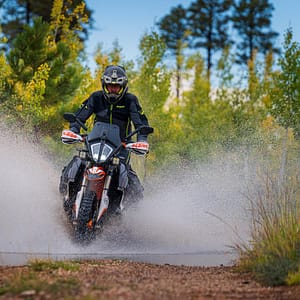A KTM rider blasts through a puddle