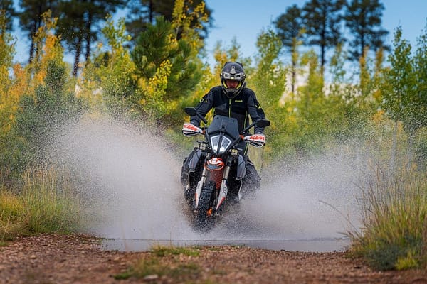 A KTM rider blasts through a puddle